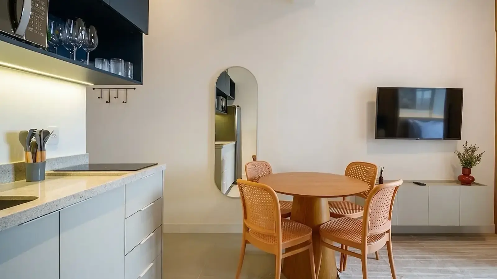 Mesa de jantar, TV e cozinha compacta de um studio mobiliado para aluguel por temporada