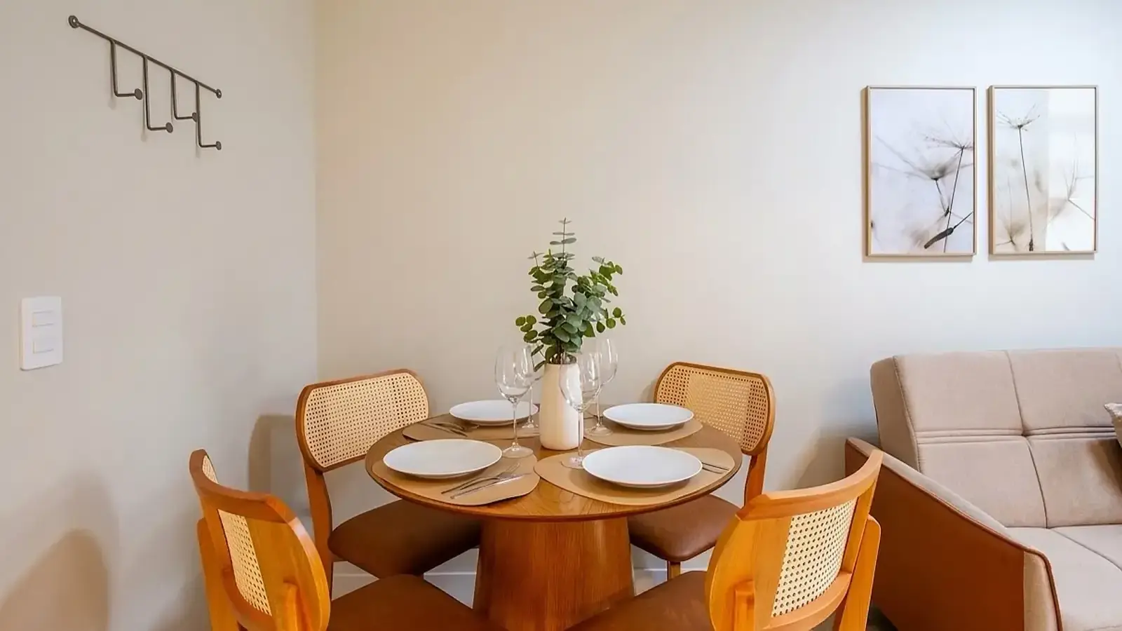 Mesa de jantar redonda com cadeiras de palha e sofá numa sala clara